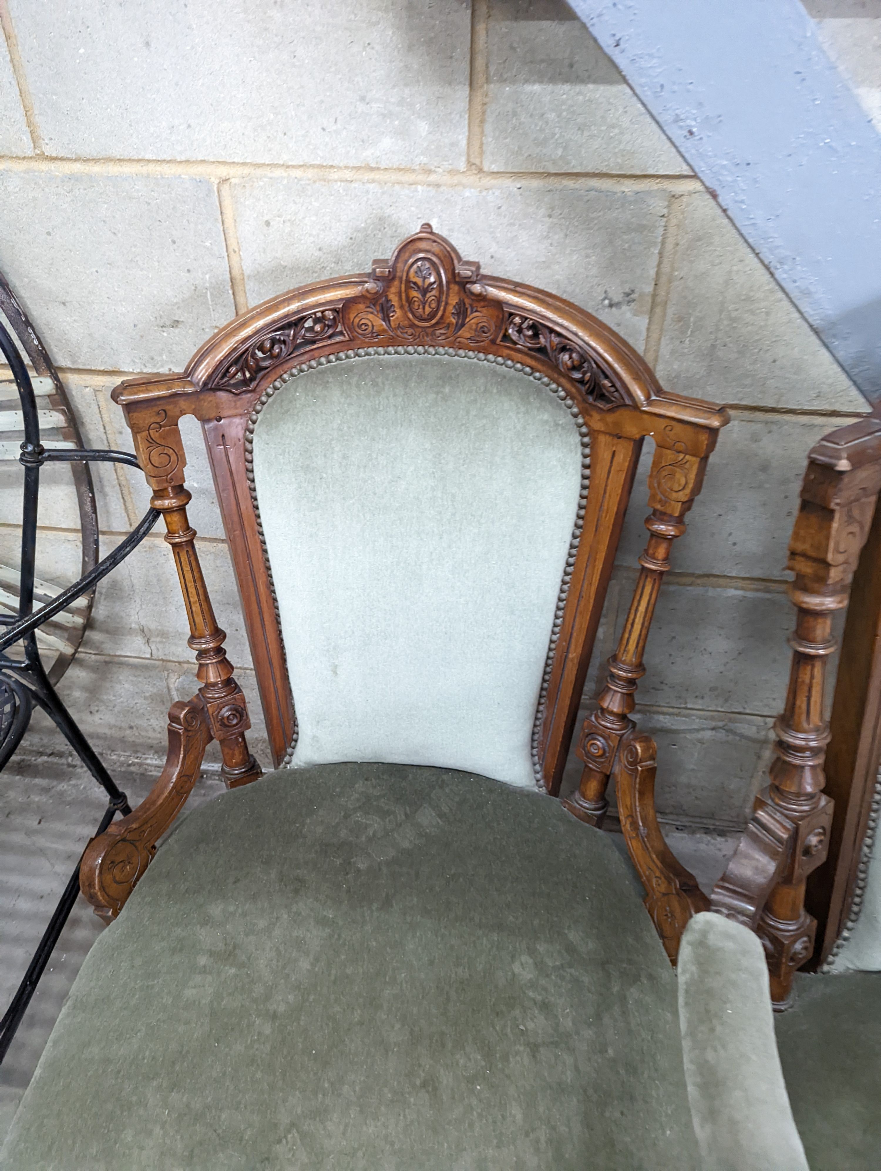 A pair of late Victorian carved walnut salon chairs upholstered in green dralon, one with arms